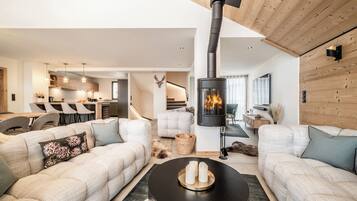 A modern living room with a central fireplace, a sofa set, and a dining area in the background.