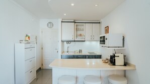 A compact kitchen with a sink, microwave, and a small island with stools.