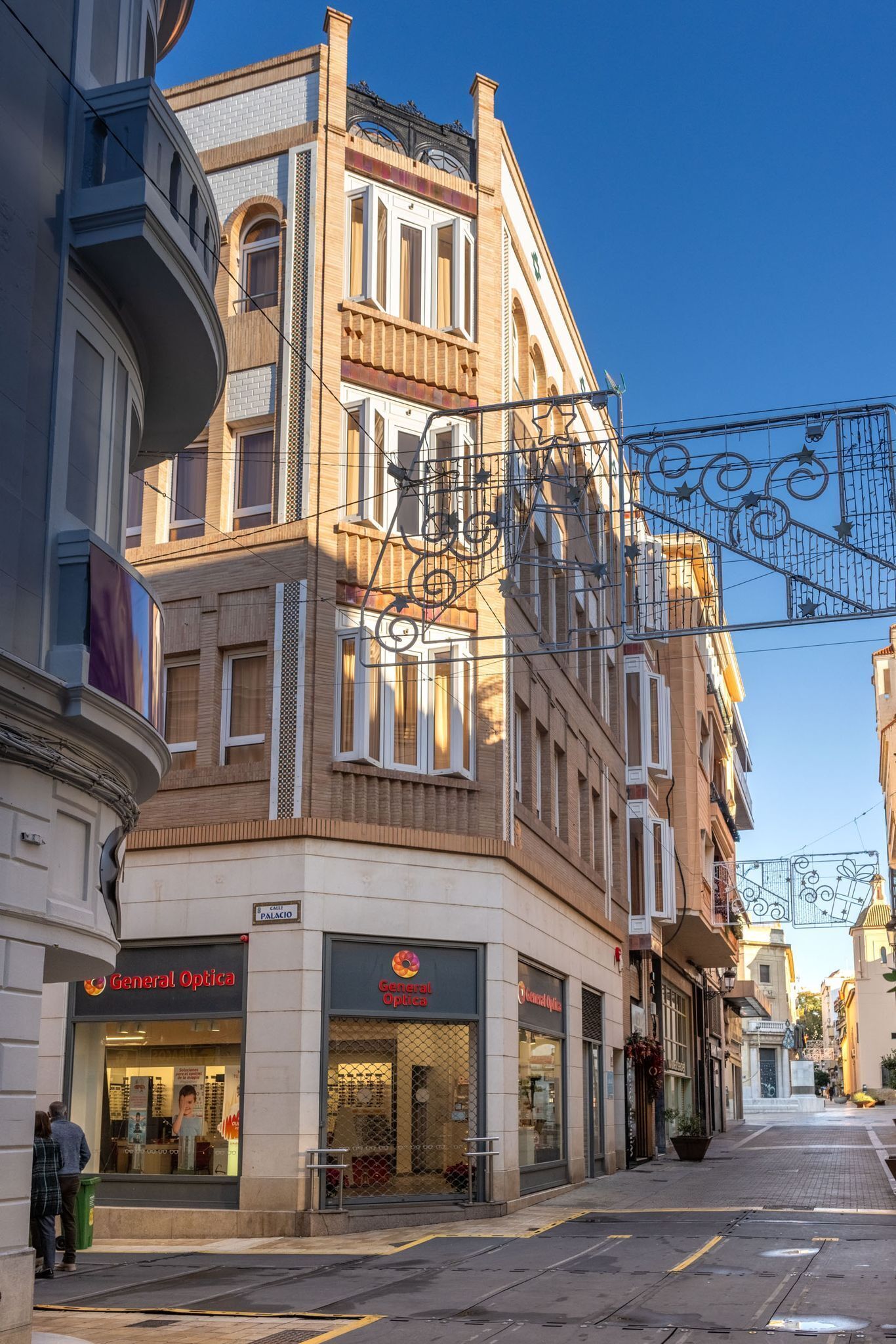 Vista de una calle con un edificio que tiene una tienda 'General Optica' en la planta baja.