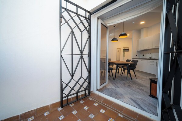 A modern kitchen with white cabinets, a wooden dining table, and black chairs. - William Martin Apartments (Huelva)