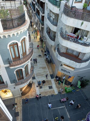 A multi-level commercial building with a central open plaza, multiple balconies, and a BBVA bank branch. - William Martin Apartments (Huelva)