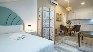 A hotel room with a bed, a desk, and a dining area. - William Martin Apartments (Huelva)