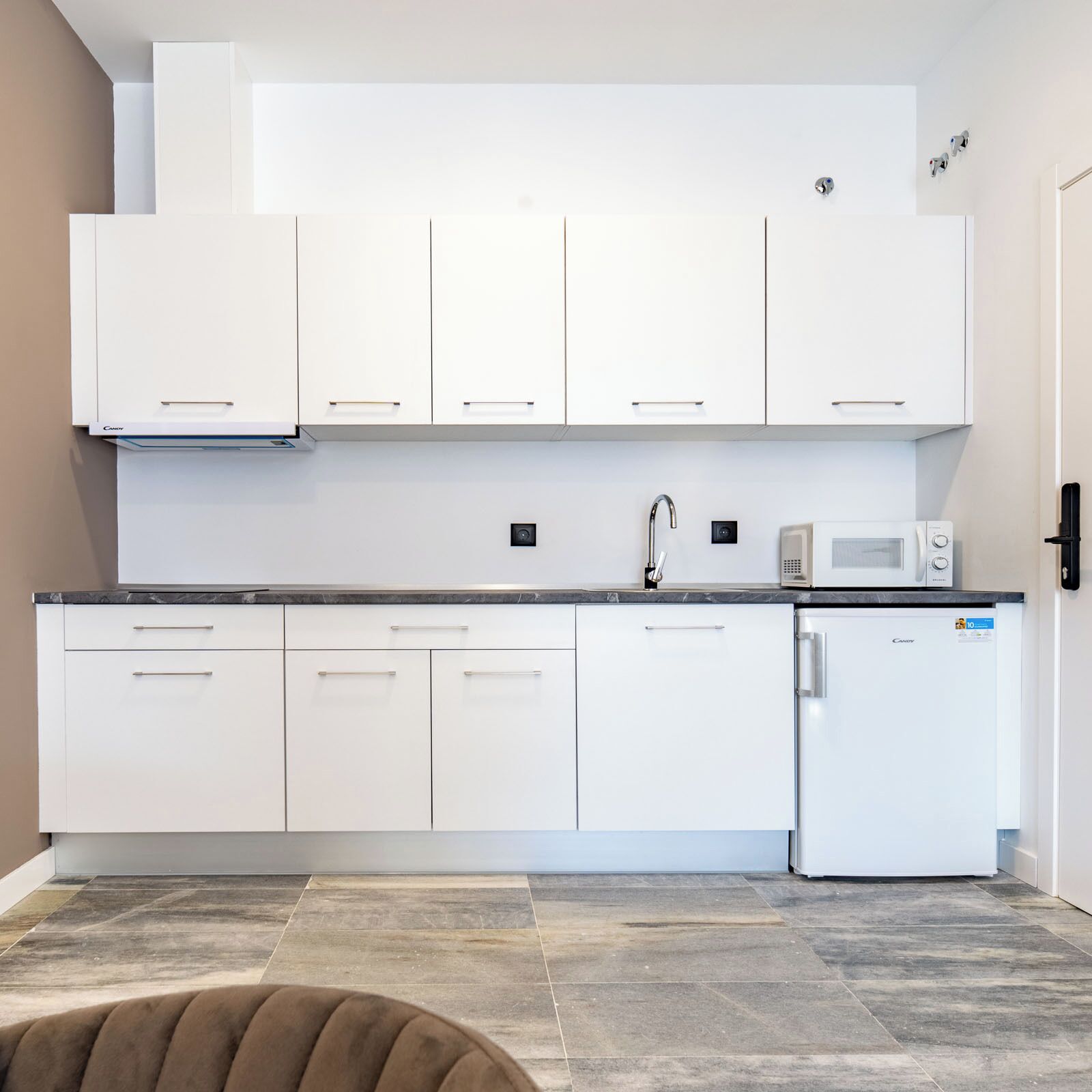 Una cocina moderna con armarios blancos, microondas integrado y refrigerador.
