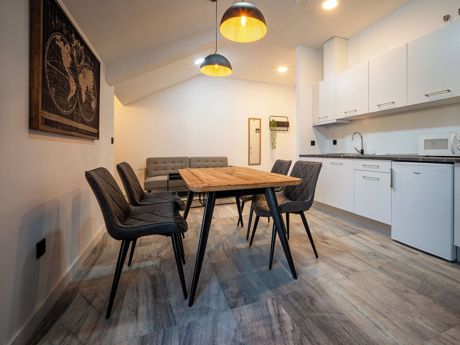 A modern kitchen with white cabinets, a wooden dining table, and black chairs.