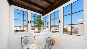 Una stanza con tavolo e sedie, una finestra che si affaccia su edifici e un soffitto con travi in legno.