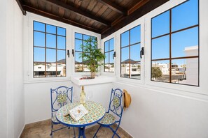 Una habitación con una mesa y sillas, un ventanal con vistas a edificios y un techo con vigas de madera.