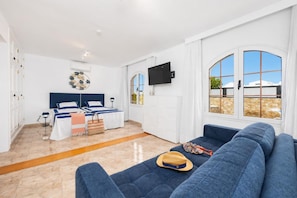 A modern hotel room with a bed, a sofa, a TV, and a large window. - Villa Eugina - Three Bedroom Villa, Sleeps 6 (Tias)