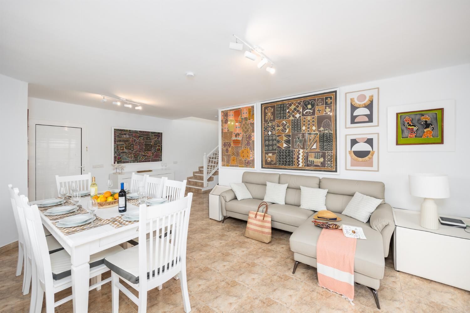 Een moderne woonkamer met een eethoek, met een bank, een salontafel en een eettafel voor vier personen.