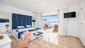 Camera d'albergo moderna con un letto grande, televisione, balcone con vista e un design pulito e minimalista.