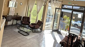 A hotel lobby with a reception desk, two armchairs, a sofa, a glass coffee table, and a chandelier. - Gran Bahía Resort (San Clemente)