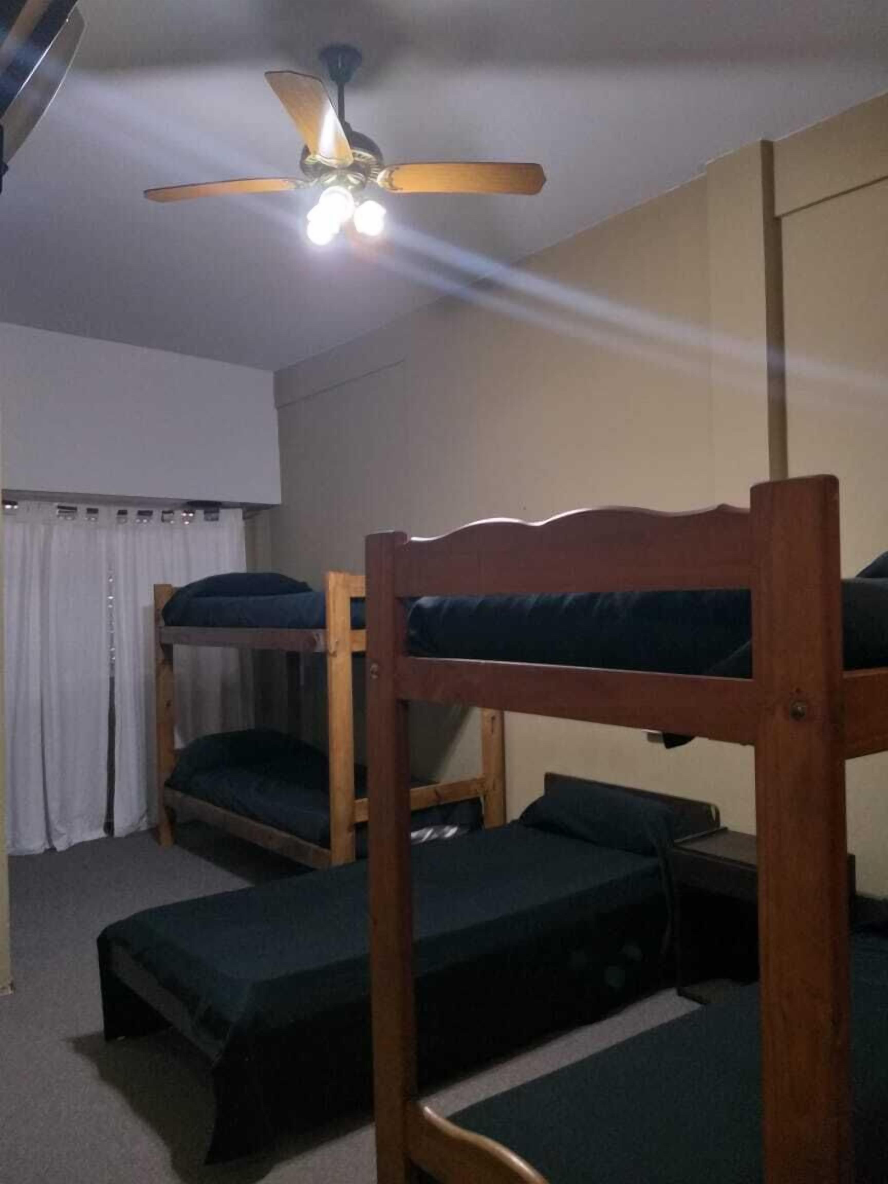 Una stanza del dormitorio con letti a castello, una ventola a soffitto e una finestra con tende.