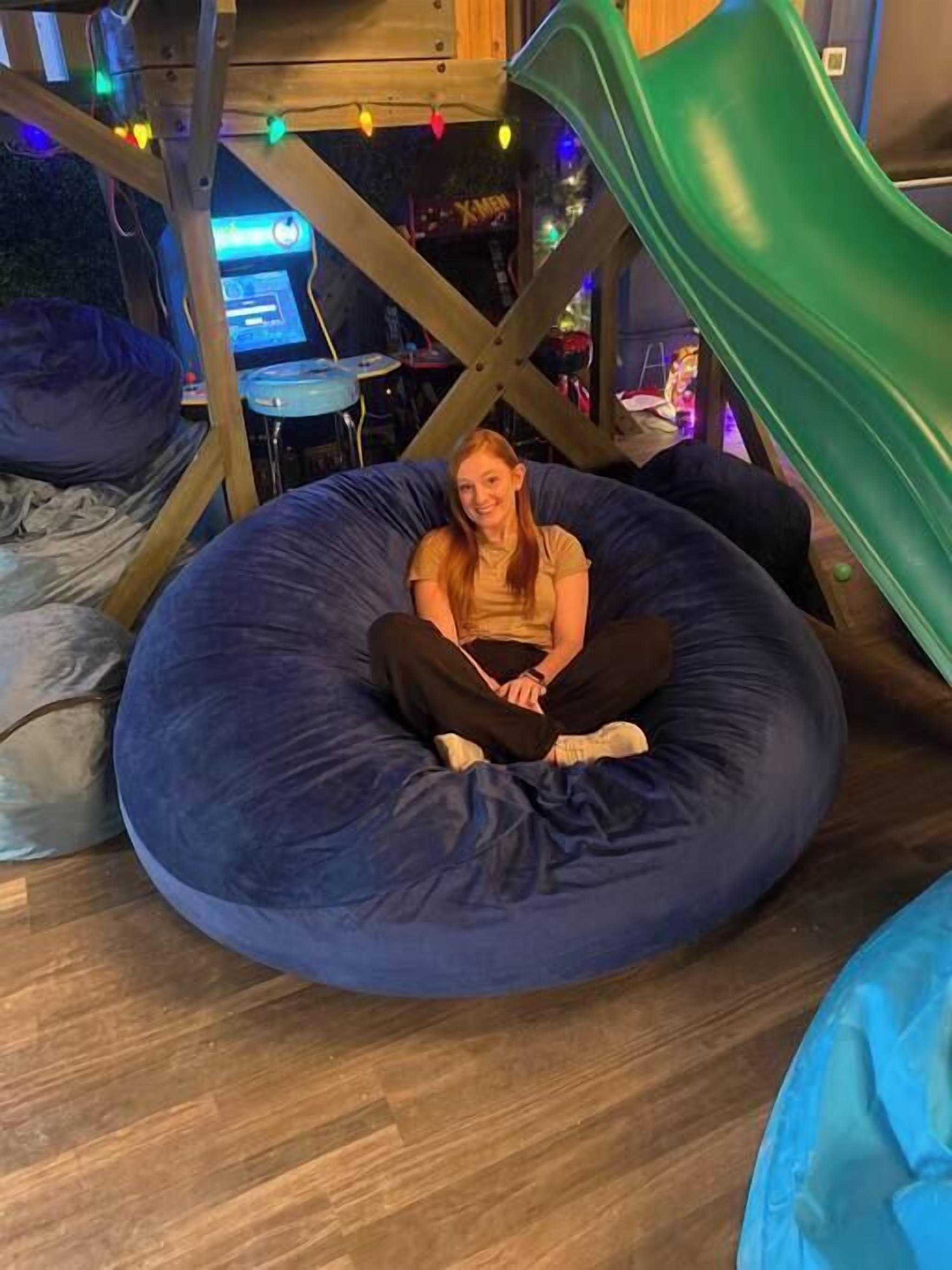 A person sitting in a bean bag chair under a green slide.