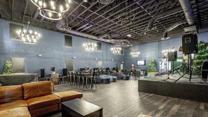 A spacious lounge area with leather sofas, a coffee table, and a stage with musical equipment. - Treehouse & Theater Arcade at Rock Spring Resort (Rock Spring)