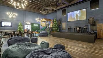 A spacious room with a stage, bean bags, and a play area with a slide.