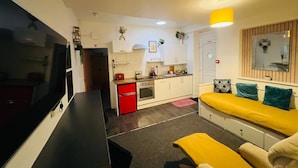 Un espace de vie compact comprenant une kitchenette, un canapé et un téléviseur.