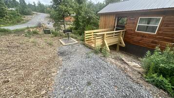 A wooden cabin with a gravel driveway, a wooden bench, and a mailbox.