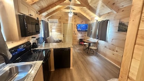 A kitchen with granite countertops, a stove, and a dishwasher. There is a dining area with a table and chairs. - Hideaway Holler - Hot Tub, Fireplace, Wi-Fi (Union Mills)
