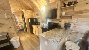 A kitchen with wooden cabinets, a granite countertop, a microwave, a stove, and a sink. - Hideaway Holler - Hot Tub, Fireplace, Wi-Fi (Union Mills)