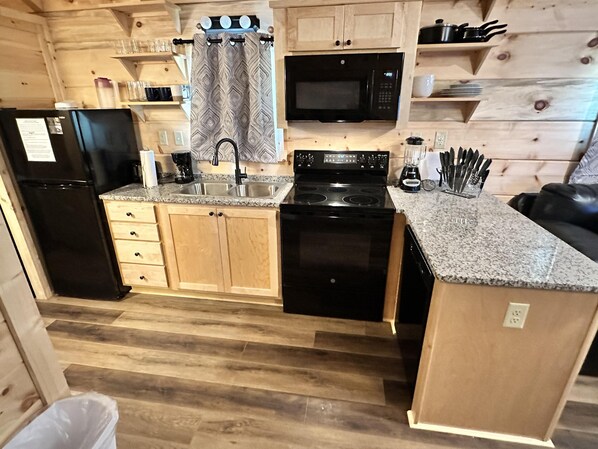A compact kitchen with a refrigerator, stove, microwave, and sink.
