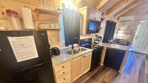A compact kitchen with a refrigerator, sink, stove, and microwave.