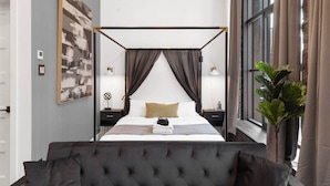 A four-poster bed with a canopy, bedside tables with lamps, a large window with curtains, and a potted plant. - Old Montreal Corner, Loft, 10 feet ceilings, 1 Bed (Montréal)
