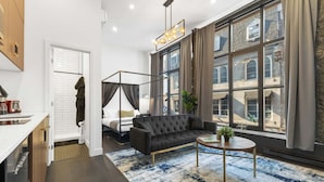 A modern hotel room with a large window, a black sofa, a small round table, and a bed with a canopy. - Old Montreal Corner, Loft, 10 feet ceilings, 1 Bed (Montréal)