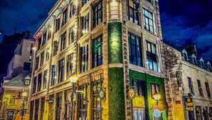 Un edificio histórico de varias plantas, con amplios ventanales y una entrada en esquina.