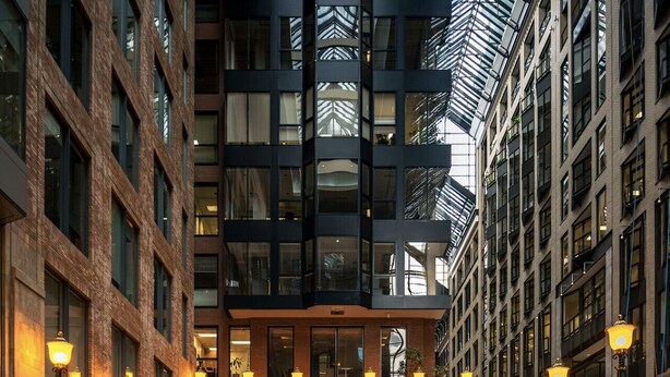 Un edificio moderno con un patio central que incluye una piscina reflectante y una estatua.