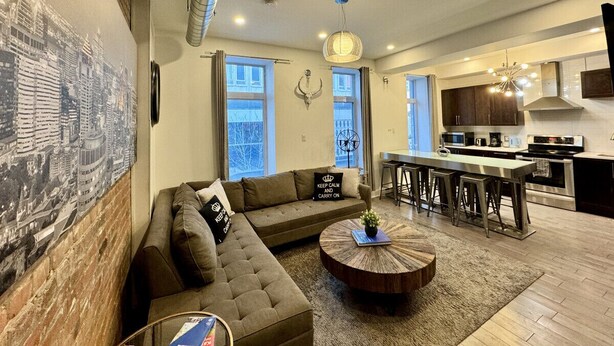 A modern living room with a sectional sofa, a round coffee table, and a cityscape mural on the wall.