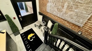A reception area with a black and gold logo, a brick wall with a map, and a staircase with a railing.
