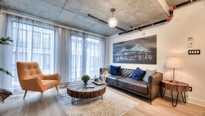 Una sala de estar moderna con un sofá, sillón, una mesa de centro y un cuadro en la pared.