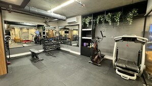 Une salle de sport équipée de matériel d’exercice, d’un tapis de course et d’un miroir.