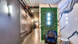 Een moderne hal met een groene wand waarop '380' staat en een blauwe stoel.
