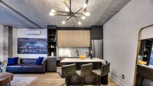 Een moderne keuken met een centraal eiland, barkrukken en een zithoek met een bank en salontafel.
