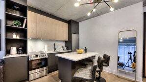 Een moderne keuken met een centraal eiland, een inbouwoven en een eethoek met twee stoelen.