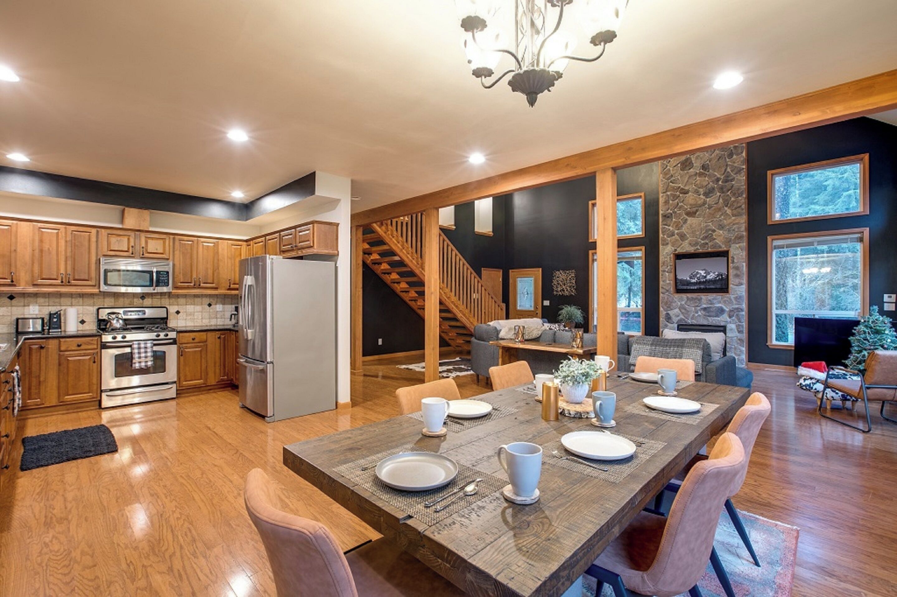 A modern kitchen with wooden cabinets, stainless steel appliances, and a dining area with a large wooden table and chairs.
