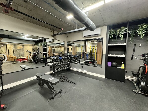 Ett gym med träningsredskap, en bänk och en spegel.