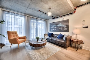 Una sala de estar moderna con un sofá, un sillón, una mesa de centro y un cuadro en la pared.