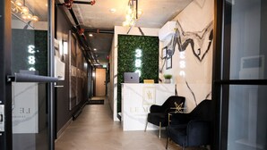 A reception area with a reception desk, black chairs, and a green wall with a laptop. - Old Montreal 1 BD Modern suite (Montréal)