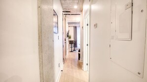 A narrow hallway with a wooden floor, white walls, and a door on the right. - Old Montreal 1 BD Modern suite (Montréal)