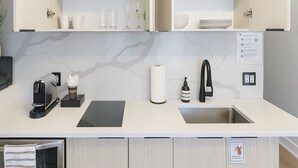 A modern kitchen with white cabinetry, a black countertop, a coffee machine, a sink, and a towel rack. - Old Montreal 1 BD Modern suite (Montréal)