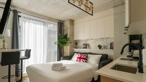 A hotel room with a bed, a desk, a chair, a sink, and a plant. - Old Montreal 1 BD Modern suite (Montréal)