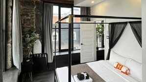 Een moderne slaapkamer met een groot bed, een stenen muur en uitzicht op de stad.