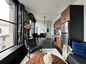 A modern living room with a sofa, a coffee table, and a dining area with chairs. - Luxury 2BD Loft-Old Montreal 2A (Montréal)