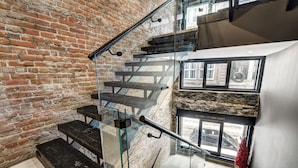 Een trap met glazen balustrades en een bakstenen muur.