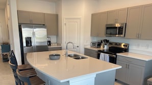 Een moderne keuken met een centraal eiland, roestvrijstalen apparatuur en een inbouwoven.