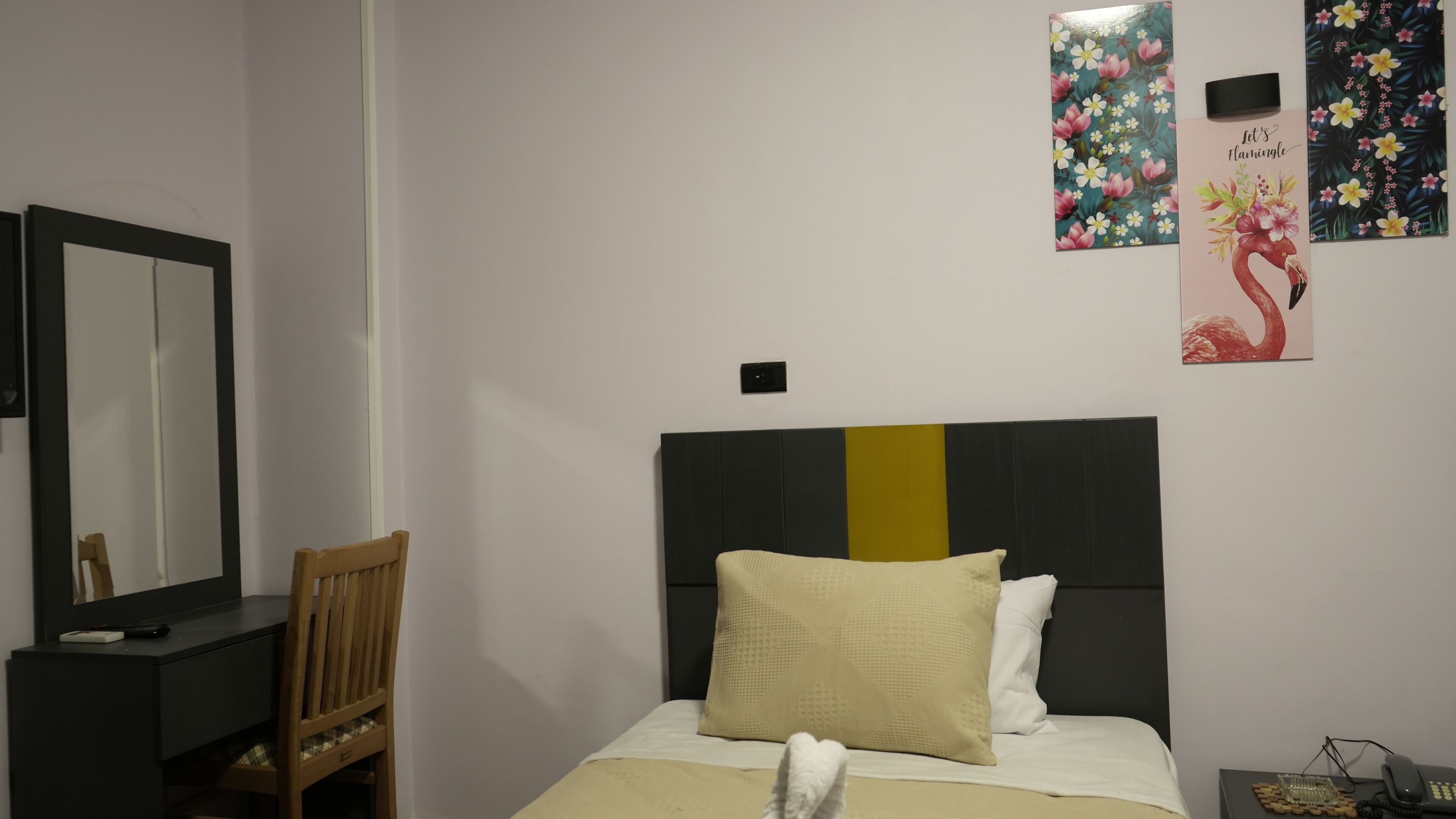A bedroom with a bed, a nightstand, a chair, a dresser, and a mirror.