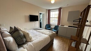 A modern bedroom with a bed, bedside tables, a TV, and a window with curtains. - Snug studio flat in Camden (Greater London)