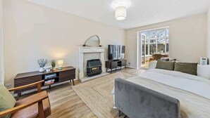 Une chambre moderne avec une cheminée, un grand lit, une télévision et un coin salon avec un banc en bois.