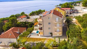 A coastal residential area with a multi-story building featuring balconies, a swimming pool, and a view of the sea.